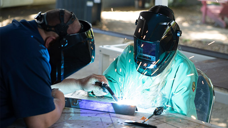 Image of two people welding at a table